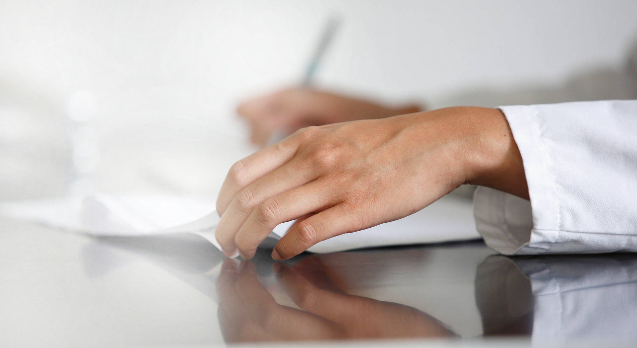 Mãos de uma médica a analisar resultados numa folha de papel