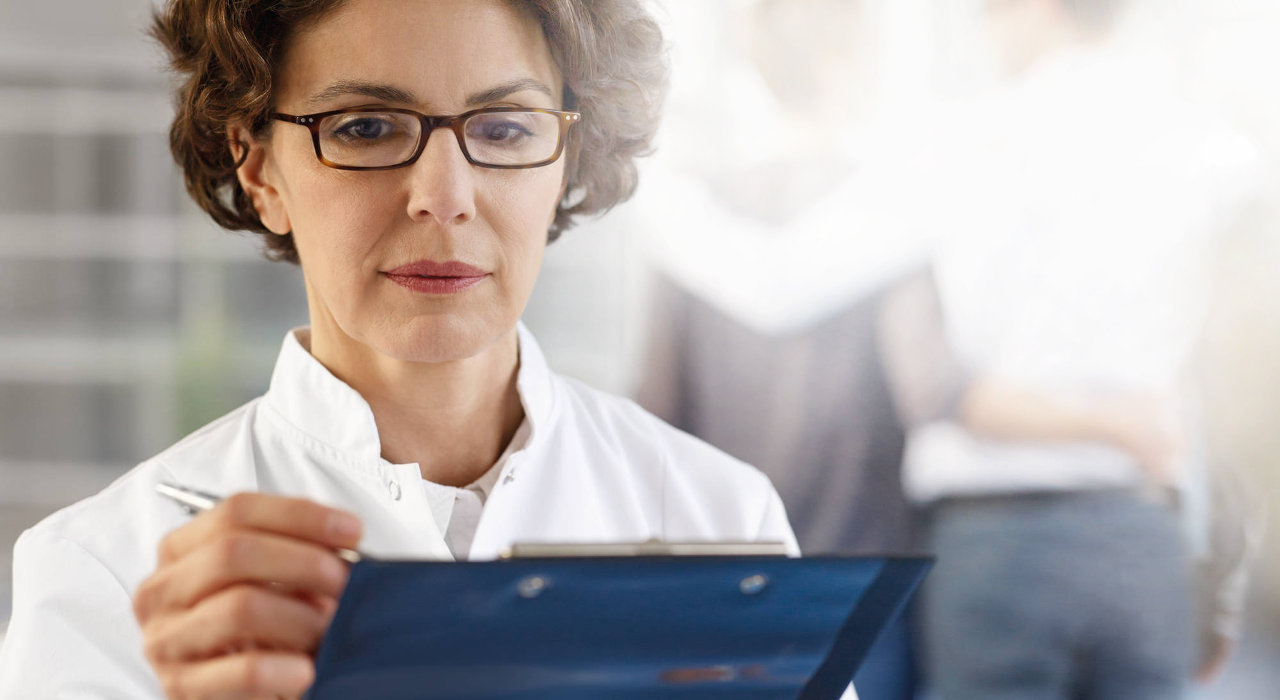 Médica analisa documento e casal afasta-se ao fundo