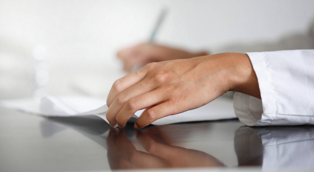 Mãos de uma médica a analisar resultados numa folha de papel